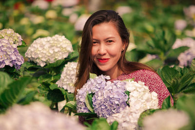 Portrait of smiling woman with flower bouquet against plants