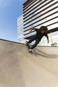 Young sportsman skateboarding on ramp at skateboard park