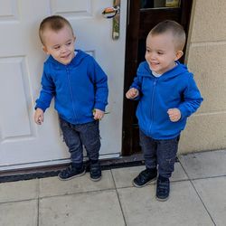 Smiling twins standing outside house 