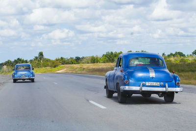 Vintage car on road against cloudy sky