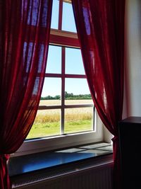 Close-up of window with red curtains at home