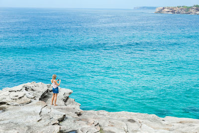 Man standing on rock by sea