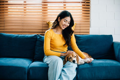 Portrait of young woman sitting on sofa at home