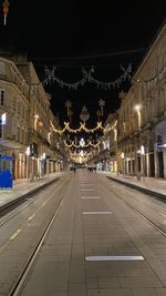 Illuminated street amidst buildings in city at night