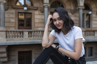 Optimistic asian girl in a white t-shirt, smiling, looking at the camera. on the street 