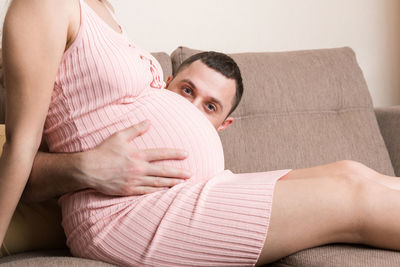 Midsection of young woman lying on sofa