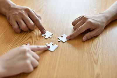 Cropped hands playing jigsaw puzzle at table