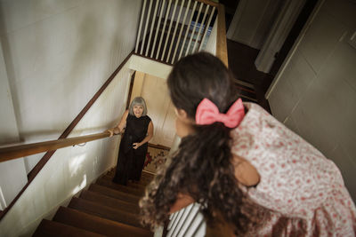 Grandmother standing on steps while looking at girl by railing