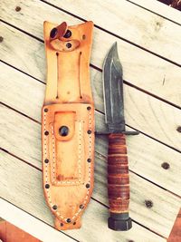 Directly above view of dagger and leather pouch on wooden table