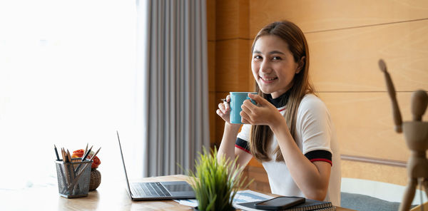 Young woman using mobile phone while sitting at home