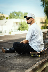 Side view of young man sitting outdoors