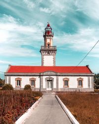 View of lighthouse by building against sky