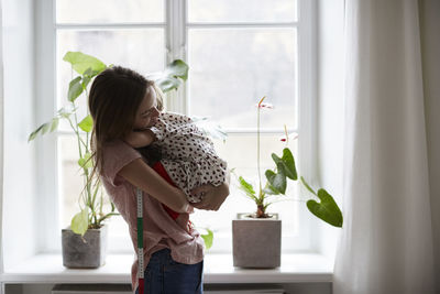 Side view of fashion designer embracing daughter while standing at home