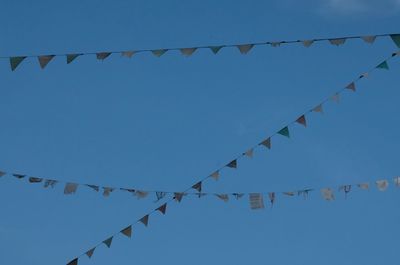 Low angle view of decorations hanging against clear blue sky