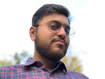 Portrait of young man looking away against sky