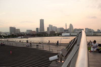 People in city against sky during sunset