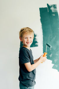 Portrait of smiling boy holding camera over white background