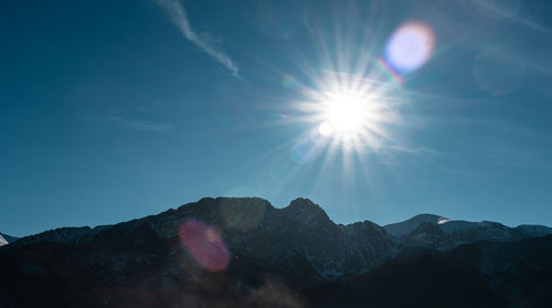 Low angle view of sunlight streaming through mountains