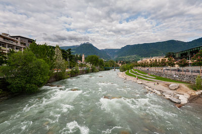 Scenic view of river by mountains against sky