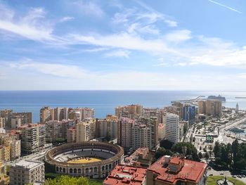 Aerial view of city buildings by sea against sky