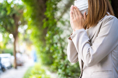 Side view of woman standing against trees