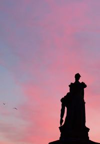 Silhouette statue against sky at sunset
