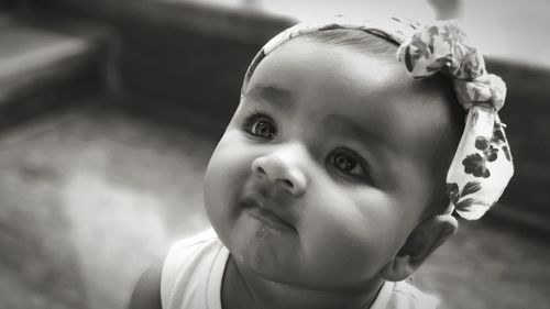 Close-up of cute baby girl looking up while sitting on floor