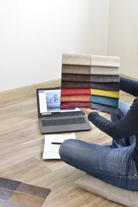 Midsection of person using laptop on hardwood floor