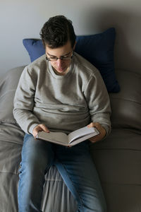 Young man using laptop while sitting on sofa at home