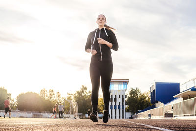 Full length of woman with arms raised against sky