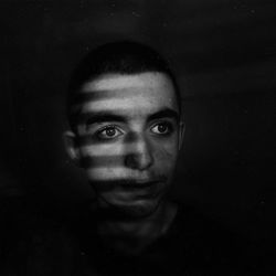 Close-up portrait of young man against black background