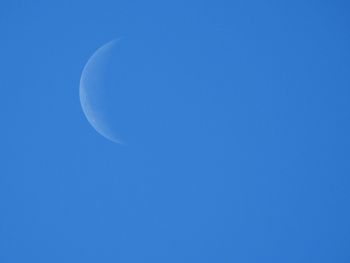 Low angle view of moon against clear blue sky