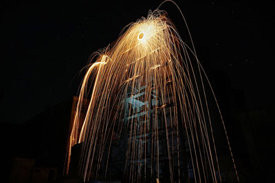 Low angle view of illuminated fireworks against sky at night