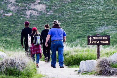 Rear view of people walking by road sign