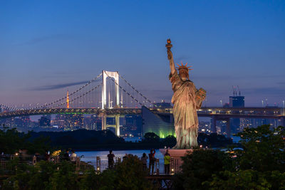 Statue of liberty against blue sky in city at night