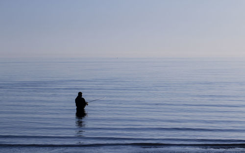 Silhouette man swimming in sea against sky