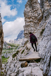 Man standing on rock by mountain against sky