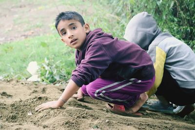 Portrait of boy with friend crouching on land