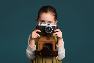 Cropped hand holding camera against blue background