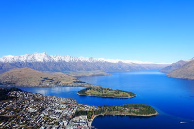 Panoramic view of lake by mountains against clear blue sky