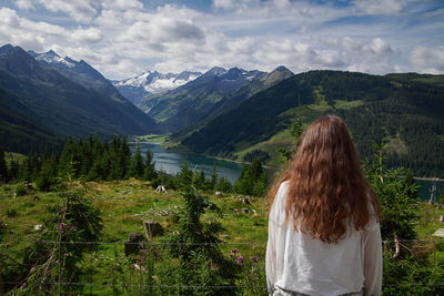 Rear view of woman looking at mountains against sky