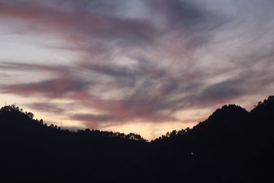 Silhouette trees against dramatic sky during sunset