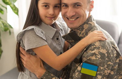 Smiling military father embracing daughter at home