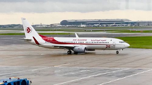 Airplane at airport runway against sky