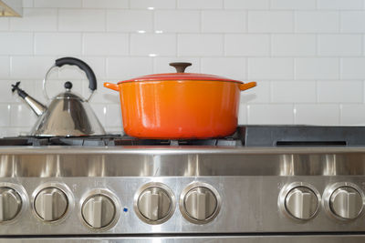 Close-up of container on gas stove by tiled wall