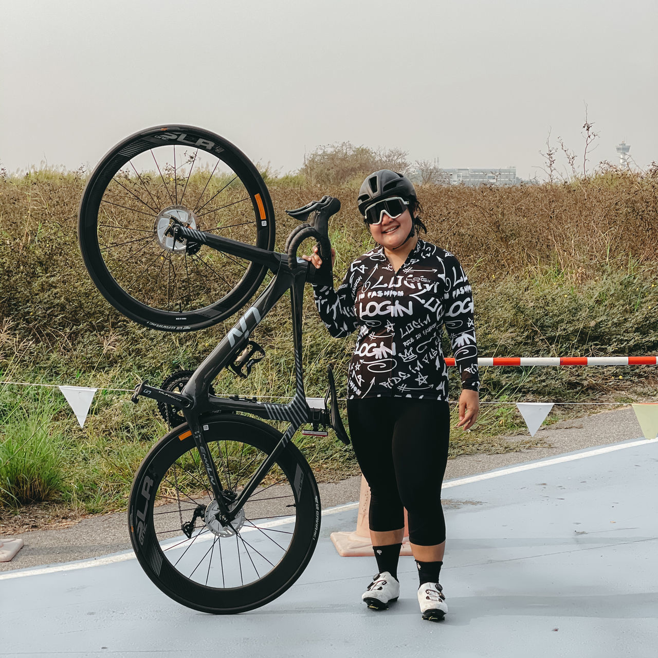 FULL LENGTH OF WOMAN WITH BICYCLE STANDING AGAINST GRAFFITI