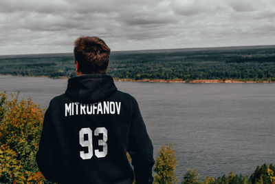 Rear view of man looking at sea against sky