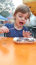 Cute girl eating food on table