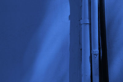 Plastered wall blue color with tubes. shadows on the wall.