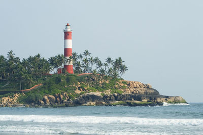 Lighthouse by sea against sky